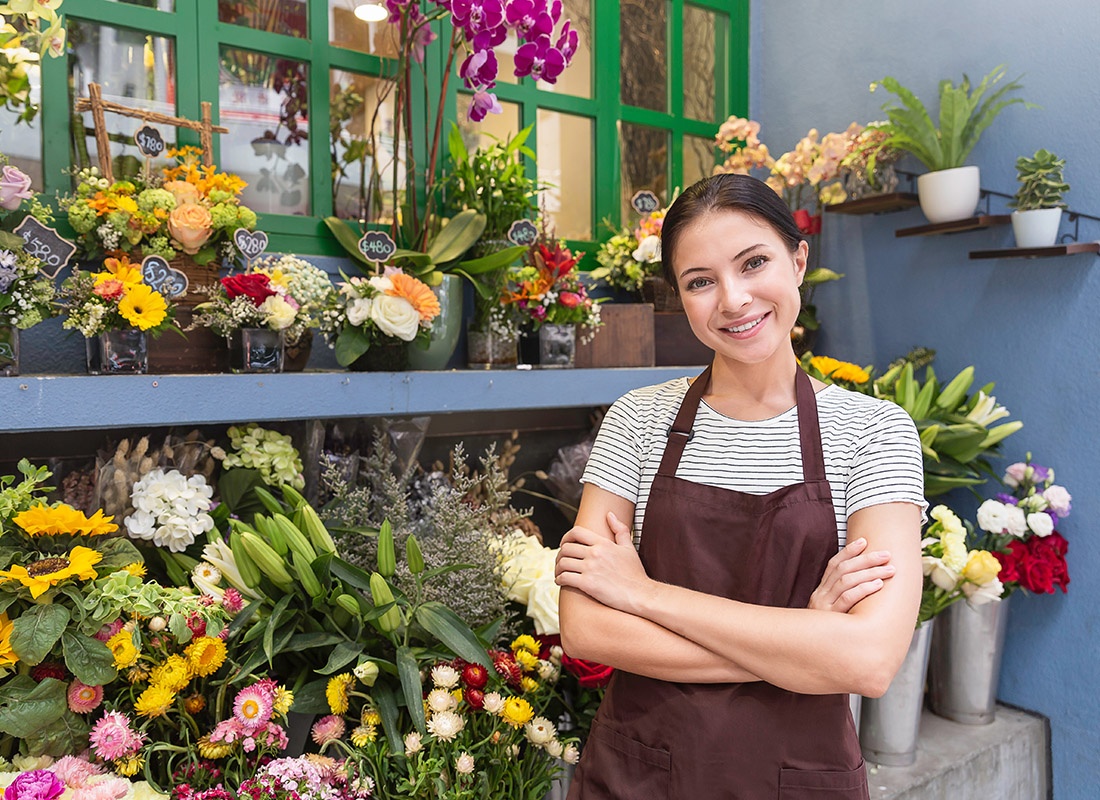 Business Insurance - Friendly Flower Shop Owner Stands in Front of a Flower Display